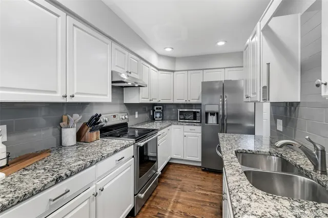 a kitchen with kitchen island granite countertop a sink stainless steel appliances and cabinets