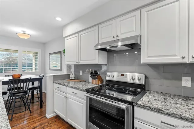 a kitchen with stainless steel appliances granite countertop a stove a sink and a white wooden cabinets