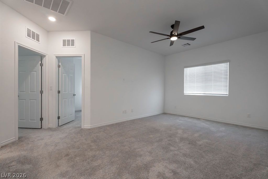 7126 Calvert Cliffs Street North Las Vegas, NV 89084 - Photo 15 of 44 A well-lit bedroom with plush carpeting and a modern ceiling fan for comfort.