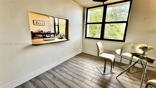 a view of dining room and livingroom with furniture wooden floor a rug and a large window