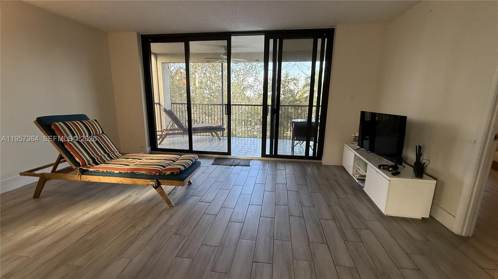 6800 Cypress Road, Unit 501 Plantation, FL 33317 - Photo 22 of 40 a living room with furniture a flat screen tv and a floor to ceiling window