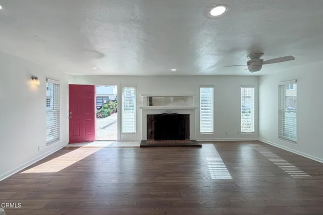 an empty room with wooden floor fireplace and windows