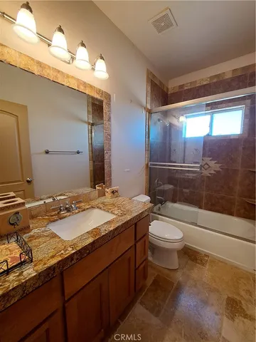 a bathroom with a granite countertop sink mirror bathtub and toilet
