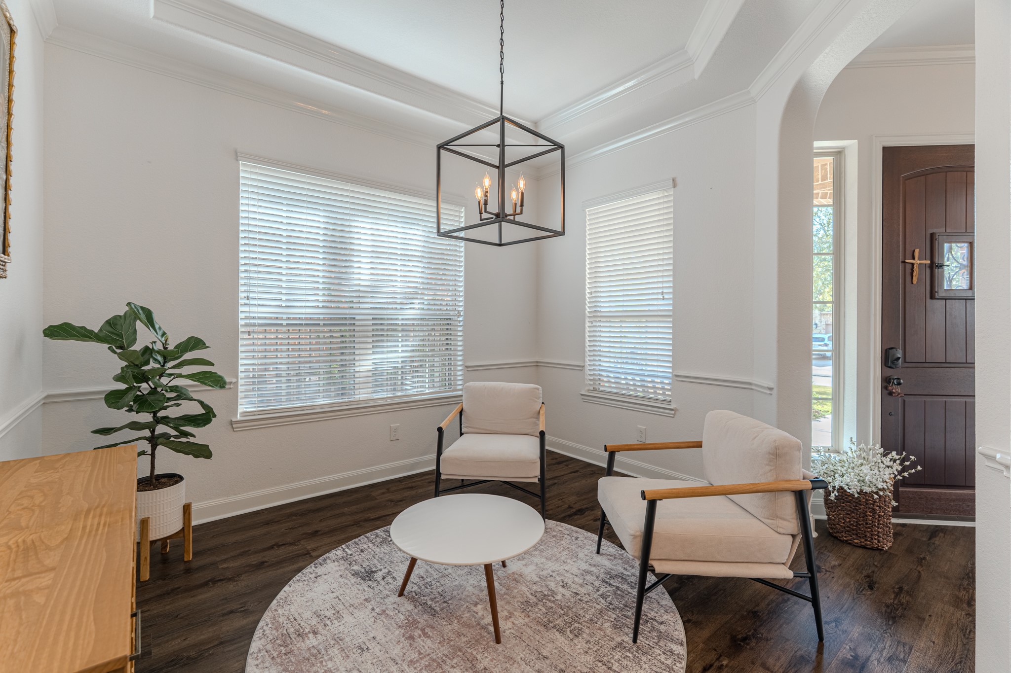 30 Fury Ranch Place The Woodlands, TX 77375 - Photo 12 of 47 This inviting entryway features elegant wood flooring, a chic modern light fixture, and ample natural light from large windows. The space includes stylish seating, a decorative plant, and a welcoming front door, providing a warm, contemporary ambiance.