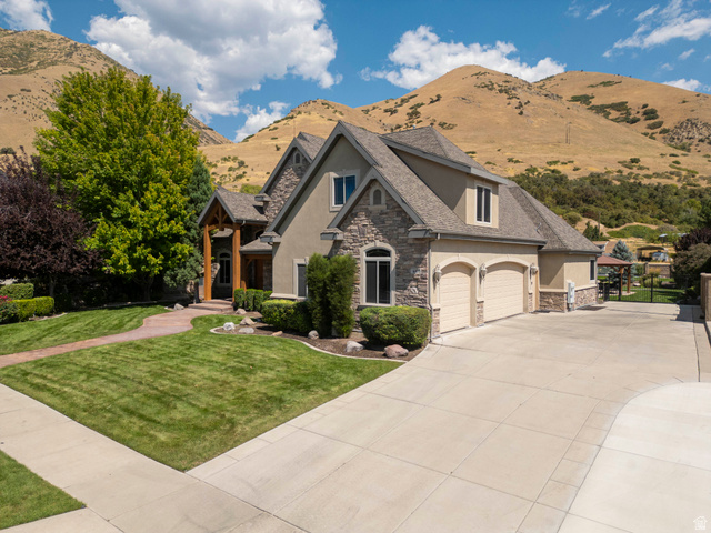 687 South 2080th Street East Springville, UT 84663 - Photo 66 of 149 Stucco and stone facade home featuring a prominent two-car garage, manicured front lawn, and mature landscaping
