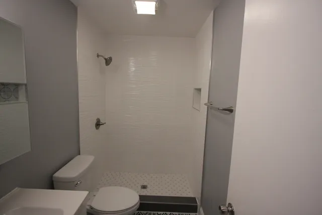a white toilet sitting next to a shower