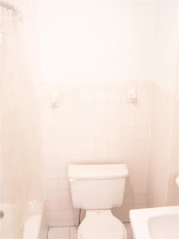 a white toilet sitting next to a white wall