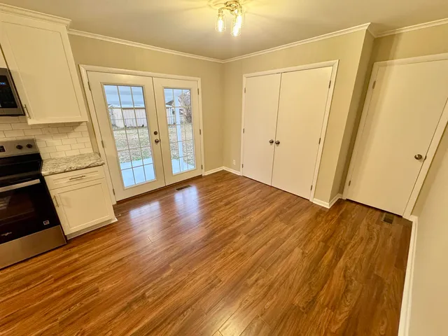 a view of an empty room with window and wooden floor