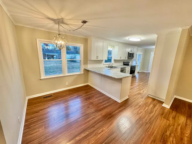 a large white kitchen with wooden floor and a window