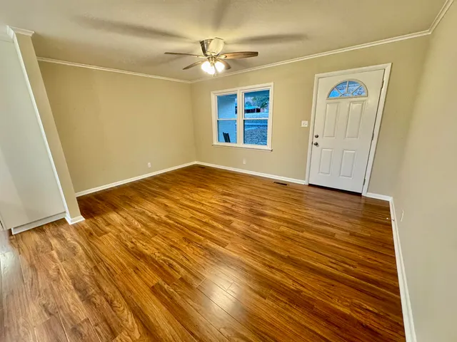 an empty room with wooden floor and windows