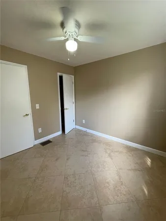 an empty room with a chandelier fan and windows
