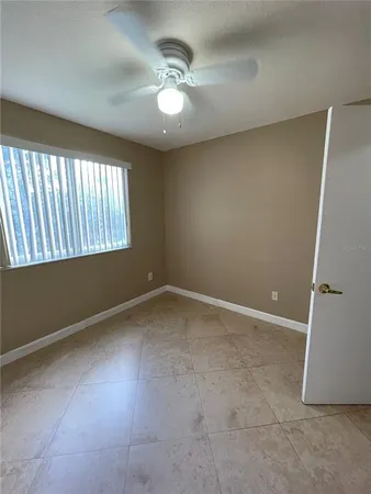 an empty room with windows and fan