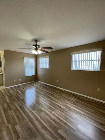 an empty room with wooden floor and windows