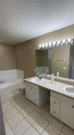 a bathroom with a double vanity sink mirror and bathtub