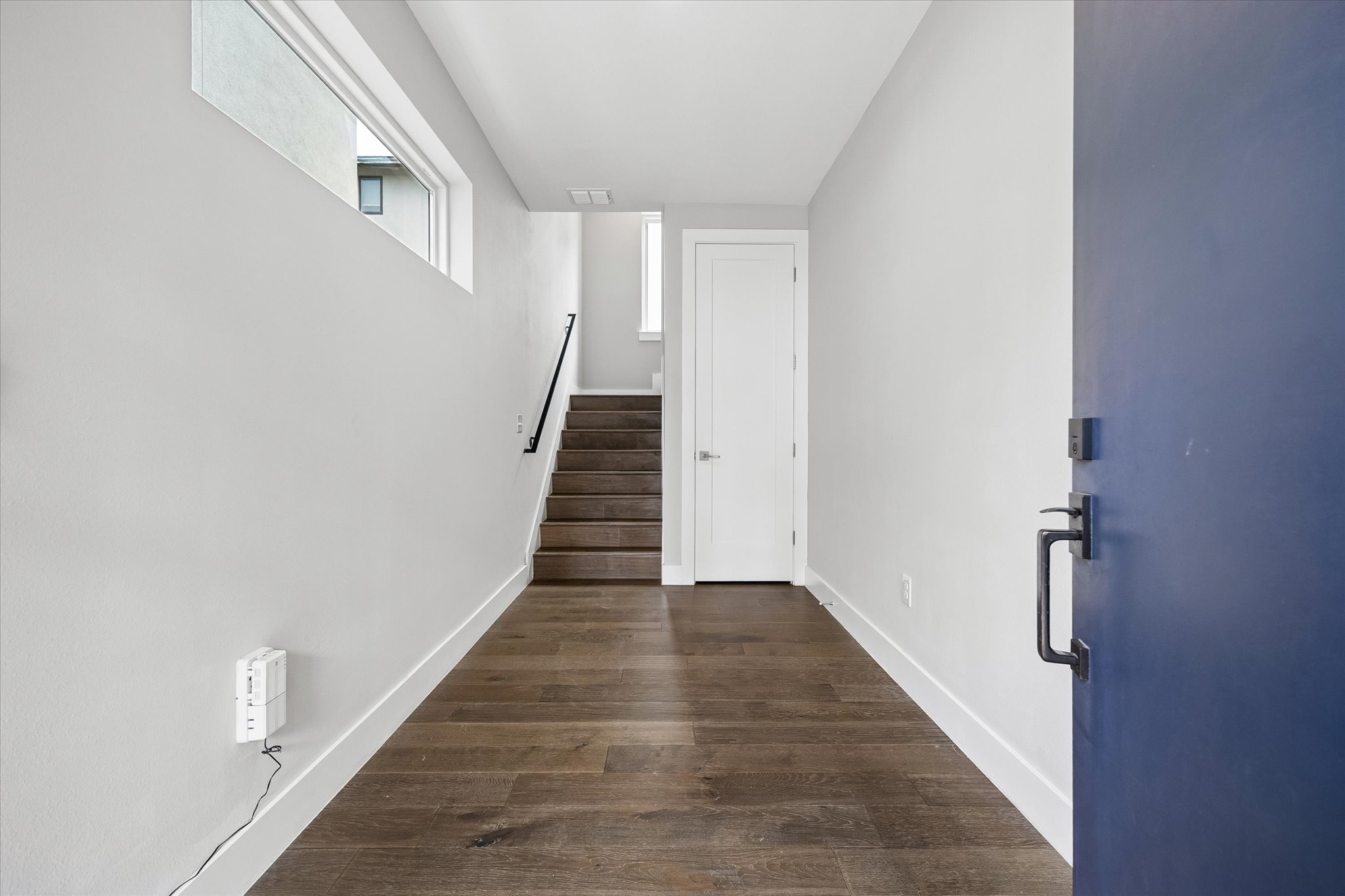 5006 Pecan Springs Road, Unit 6 Austin, TX 78723 - Photo 4 of 30 A welcoming entryway with rich hardwood flooring leads to a modern staircase and a crisp white interior door.