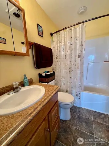 a bathroom with a granite countertop toilet sink and mirror