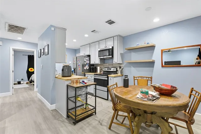a kitchen with stainless steel appliances kitchen island granite countertop a dining table chairs refrigerator and sink