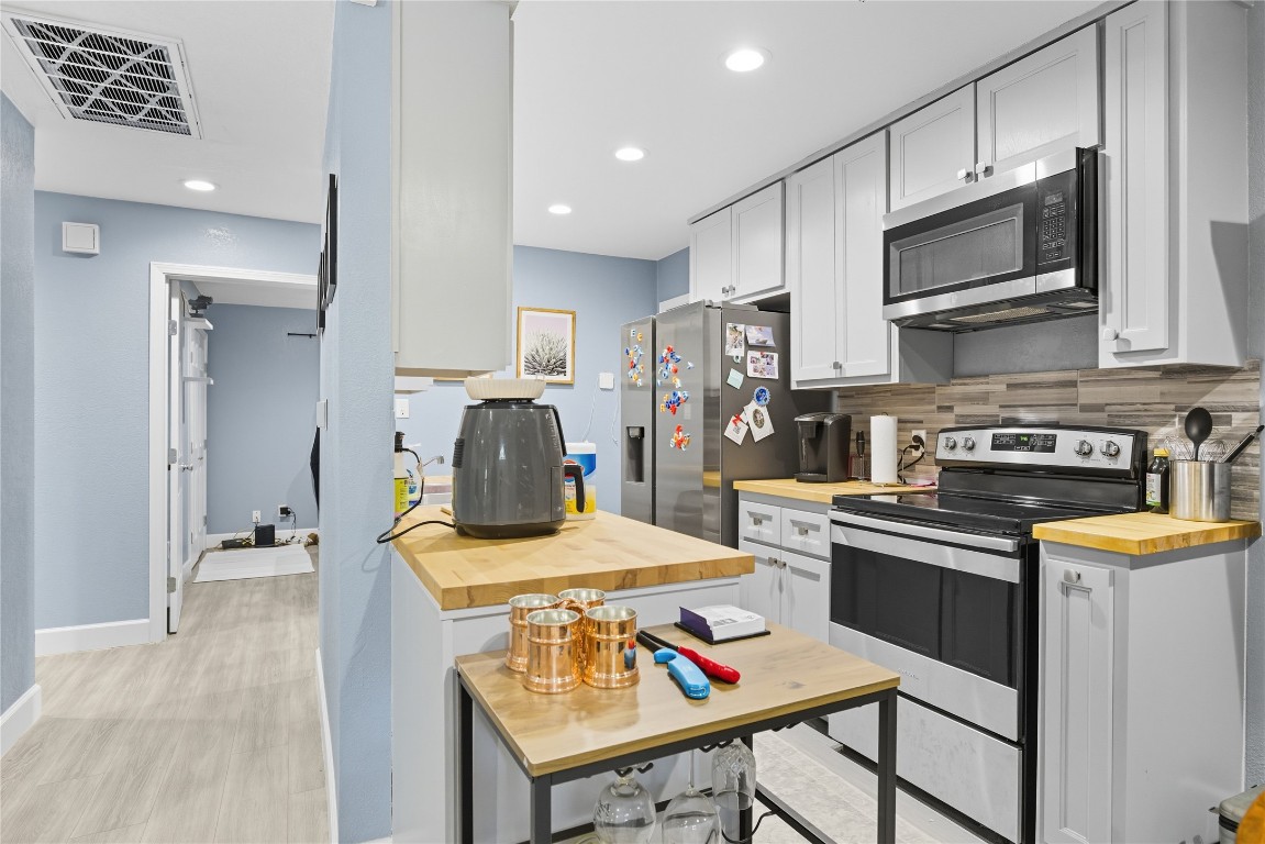 5401 Agua Caliente Cove, Unit B Austin, TX 78744 - Photo 10 of 26 a kitchen with stainless steel appliances kitchen island granite countertop a sink a stove a refrigerator cabinets and a dining table