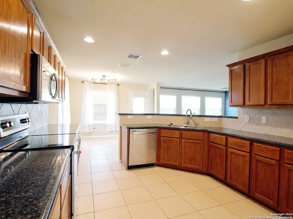 a large kitchen with stainless steel appliances granite countertop a sink and stove top oven