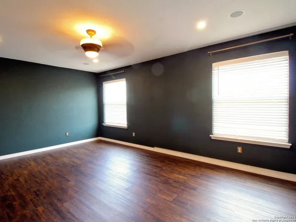 an empty room with wooden floor and windows