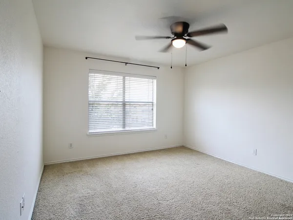 an empty room with a ceiling fan and window