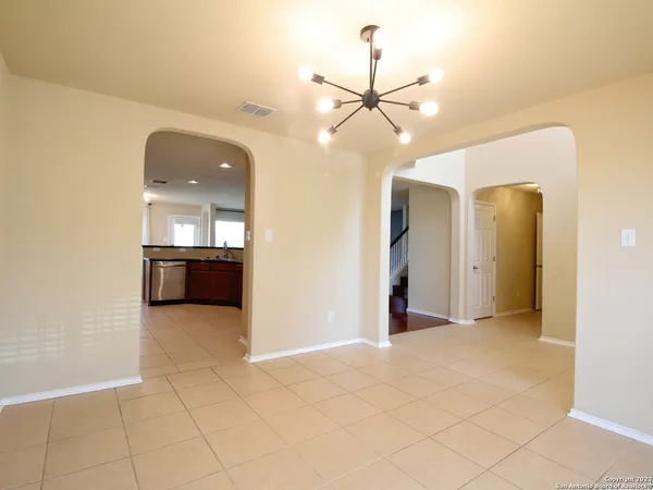 an empty room with fan and kitchen view