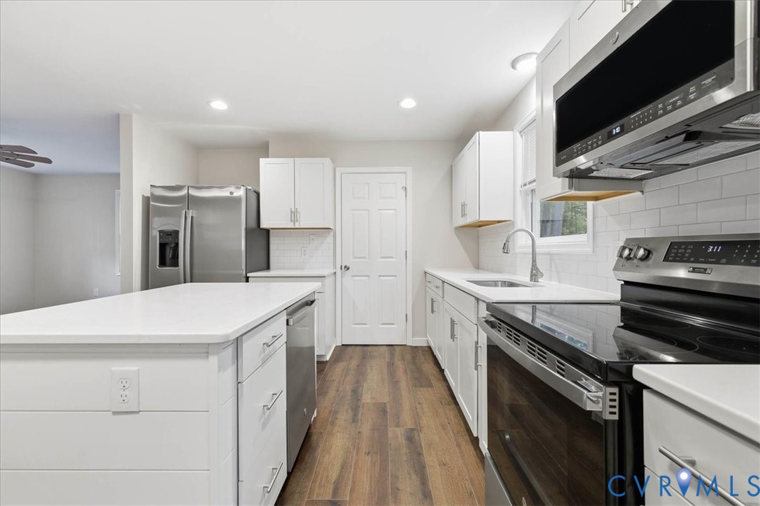 7603 Golf Course Drive Disputanta, VA 23842 - Photo 6 of 24 a kitchen with granite countertop kitchen island wooden floors appliances and white counter tops