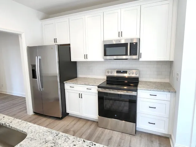 a kitchen with stainless steel appliances white cabinets and a refrigerator