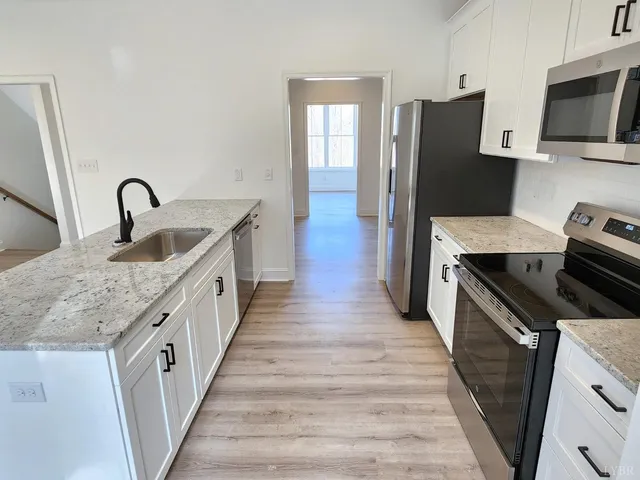a kitchen with granite countertop a refrigerator stove and sink