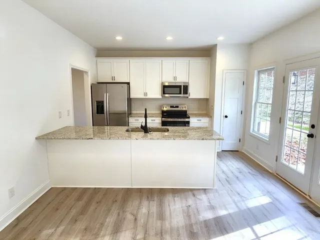 a view of kitchen with sink microwave refrigerator and cabinets