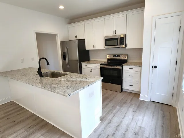 a kitchen with granite countertop a refrigerator stove and sink