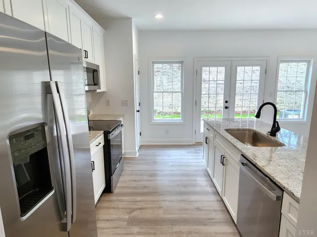 a kitchen with stainless steel appliances granite countertop a refrigerator a sink a stove and island with wooden floor