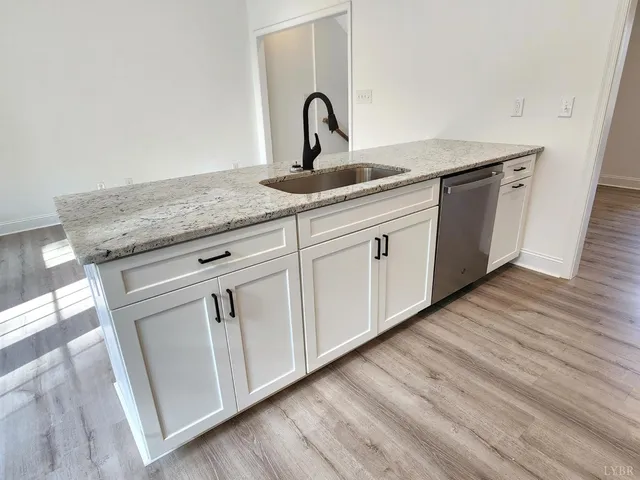 a kitchen with granite countertop white cabinets and sink