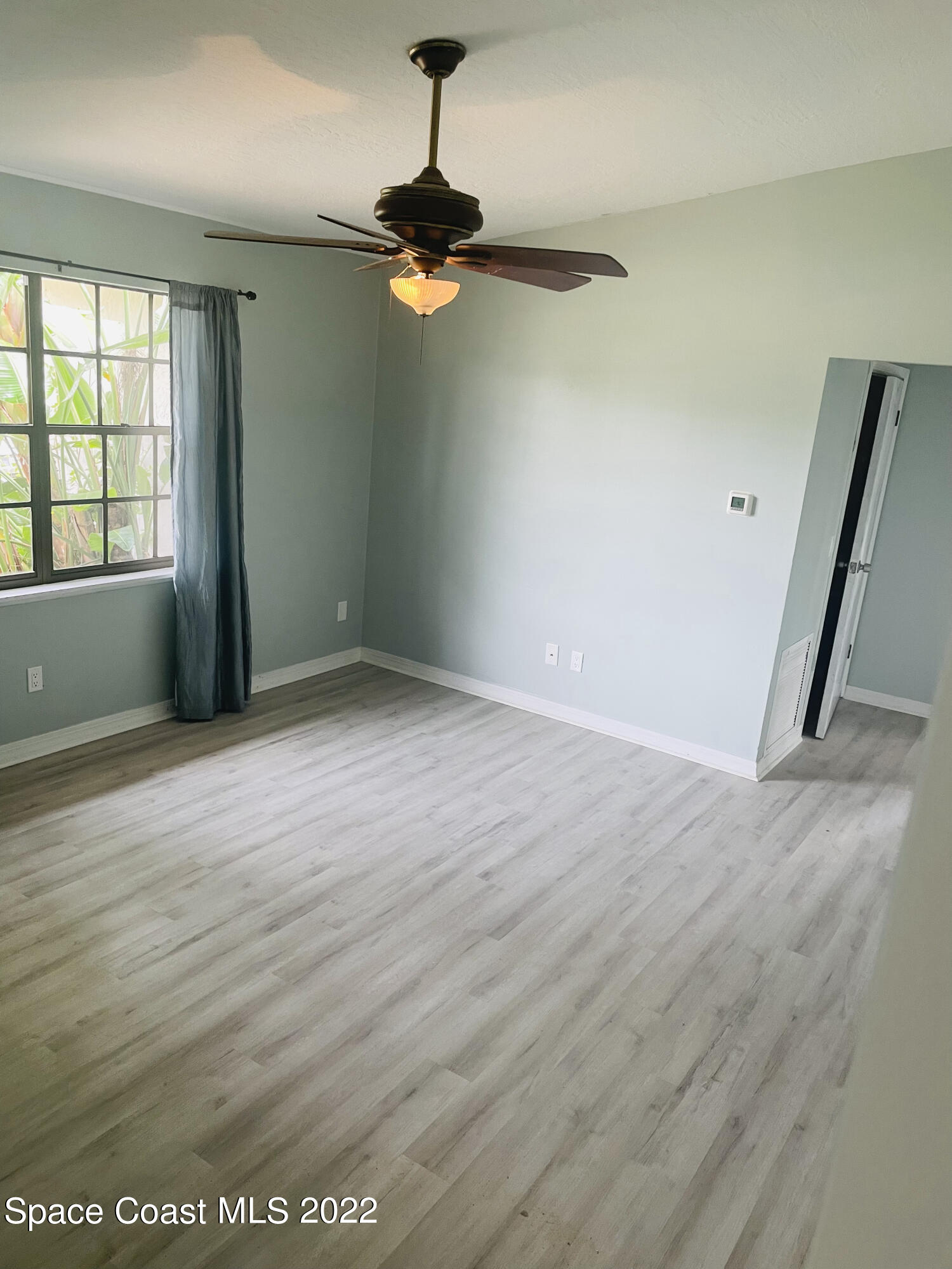 590 Rheine Road Northwest Palm Bay, FL 32907 - Photo 7 of 19 an empty room with wooden floor fan and windows