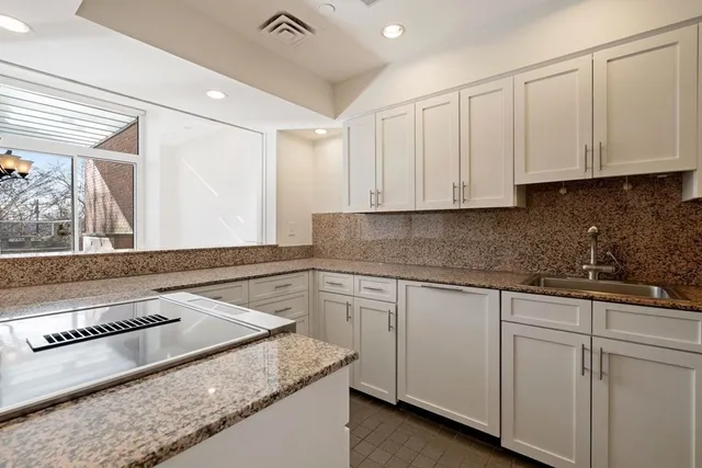 a kitchen with granite countertop white cabinets and a stove