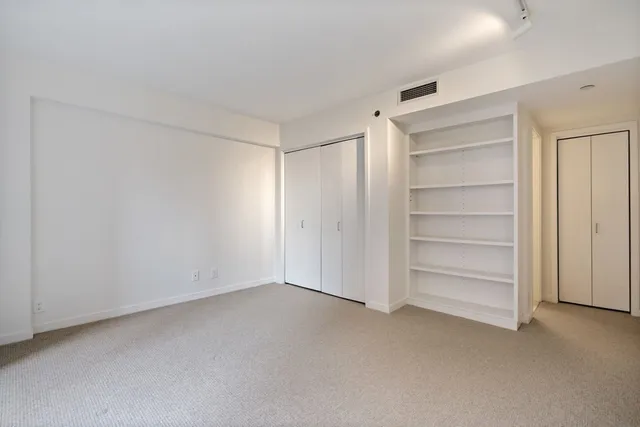 a view of an empty room with a fireplace and wooden floor