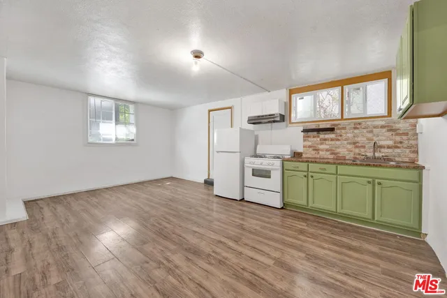 a kitchen with granite countertop wooden floors and white stainless steel appliances