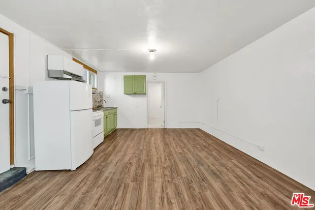 a view of empty room with wooden floor and electronic appliances