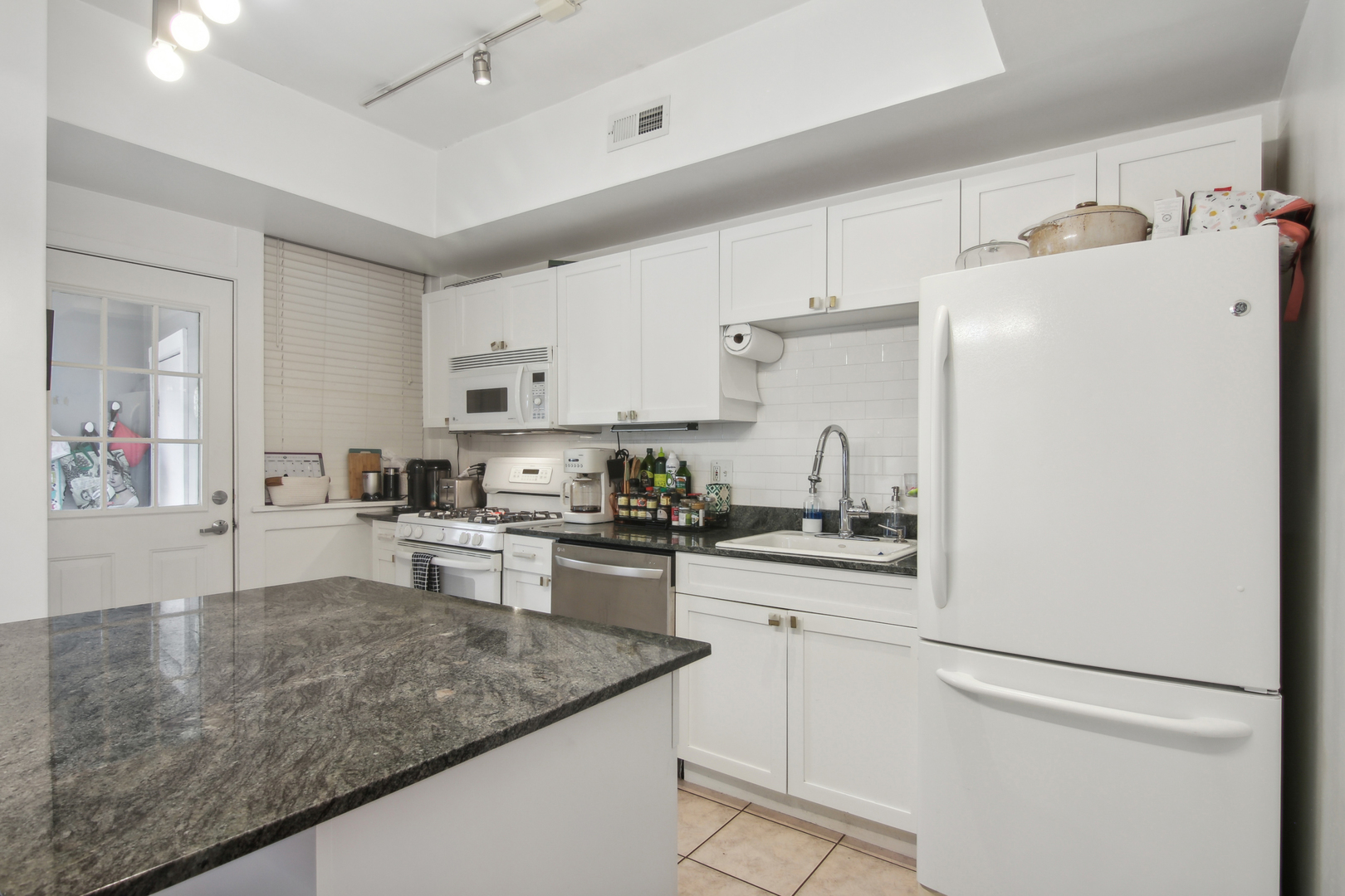 5683 North Ridge Avenue, Unit 2W Chicago, IL 60660 - Photo 13 of 23 a kitchen with white cabinets and white appliances