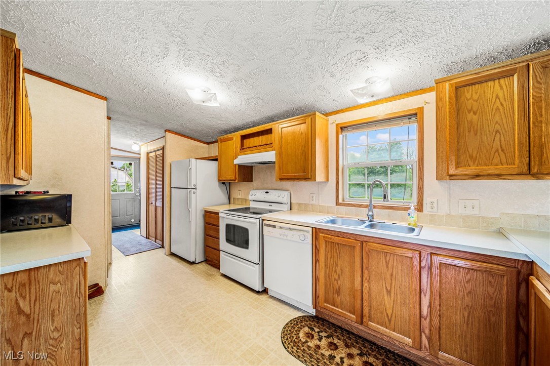 6835 Sidley Road Thompson, OH 44086 - Photo 22 of 39 Kitchen featuring white appliances, under cabinet range hood, brown cabinets, light countertops, and a textured ceiling