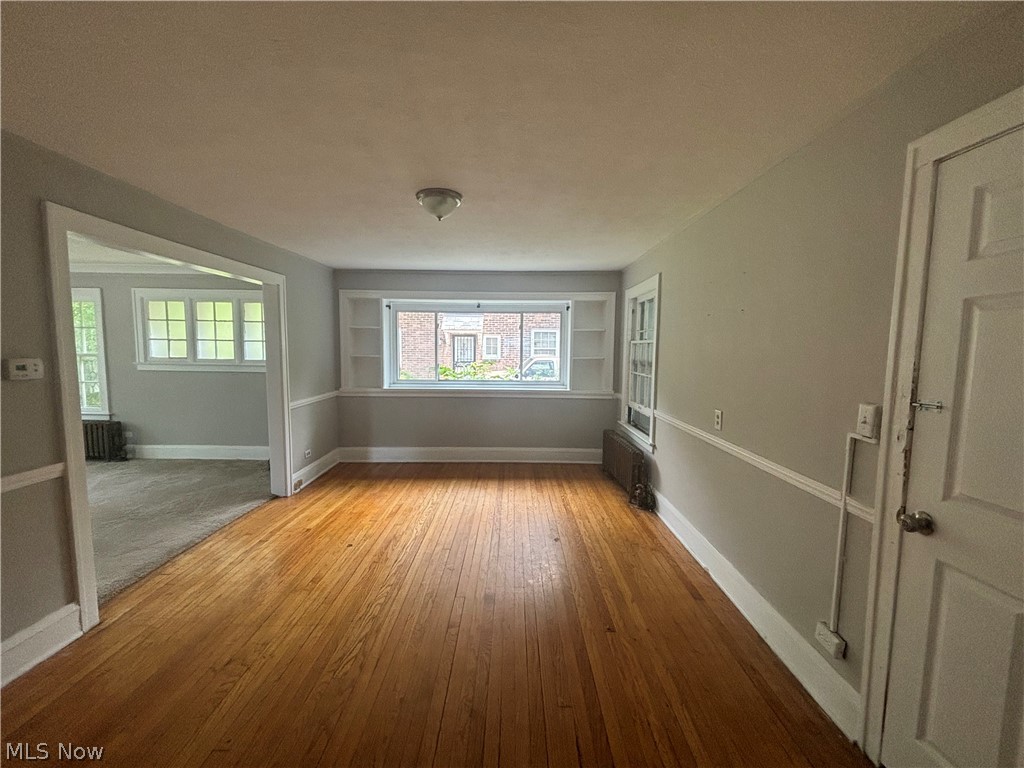 3030 Keswick Road Cleveland, OH 44120 - Photo 7 of 15 Empty room featuring built in shelves, radiator, and hardwood / wood-style floors