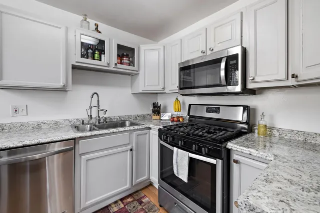 a kitchen with stainless steel appliances granite countertop white cabinets sink and stove