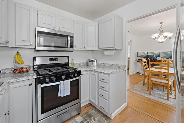 a kitchen with stainless steel appliances white cabinets and stove top oven