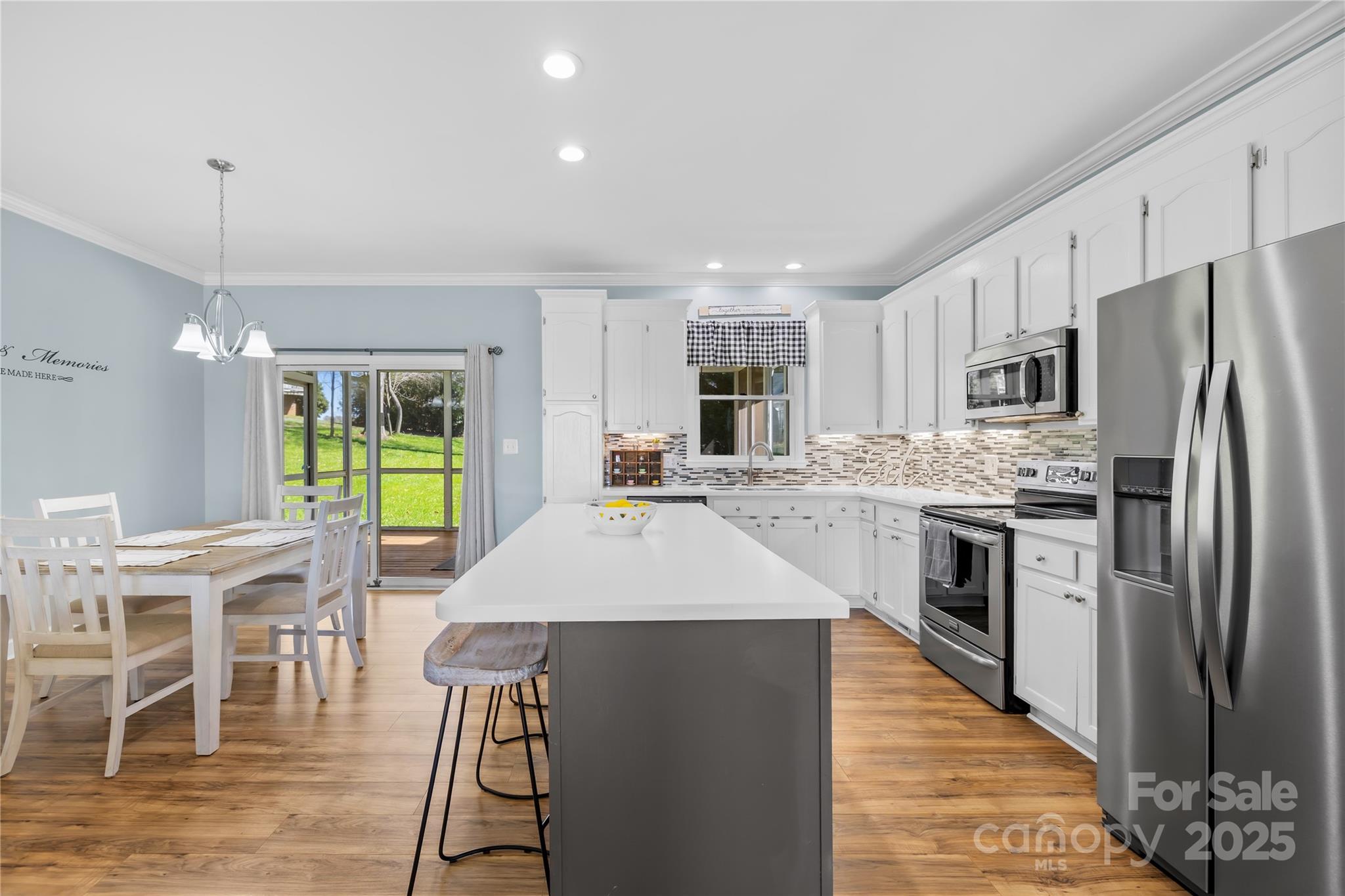675 Normandy Road Mooresville, NC 28117 - Photo 15 of 36 a kitchen with stainless steel appliances kitchen island granite countertop a refrigerator a stove a sink a dining table and chairs with wooden floor