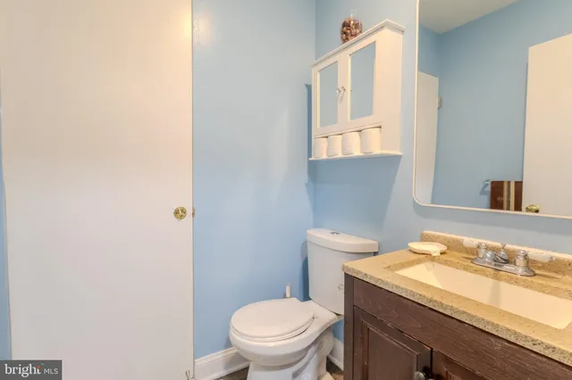 a bathroom with a granite countertop sink and a toilet