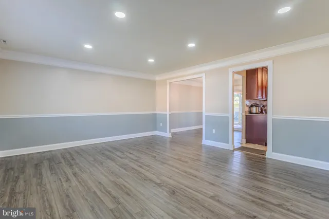an empty room with wooden floor & cabinet and windows