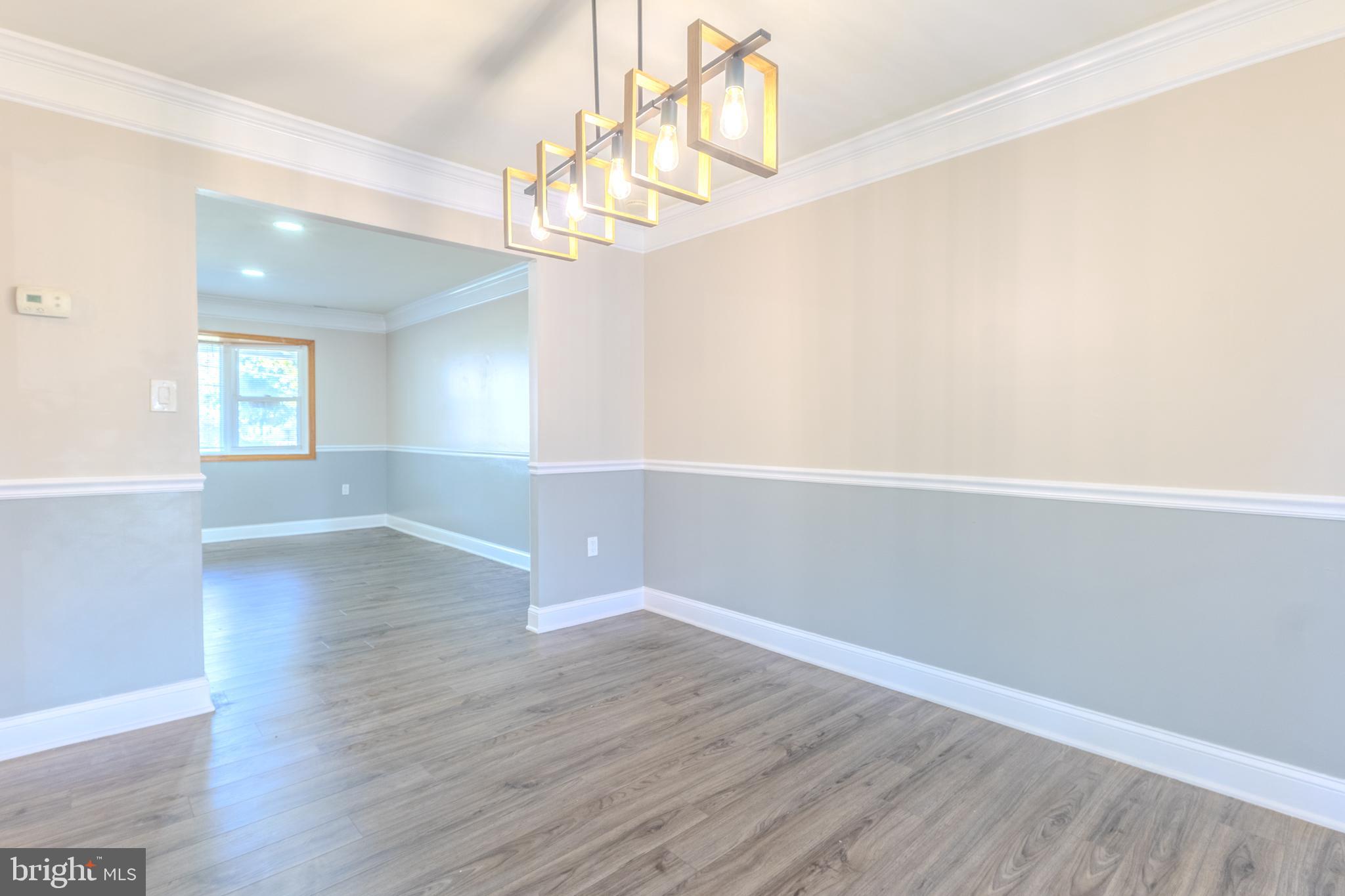 2106 North Rolling Road Windsor Mill, MD 21244 - Photo 8 of 26 an empty room with wooden floor chandelier and windows