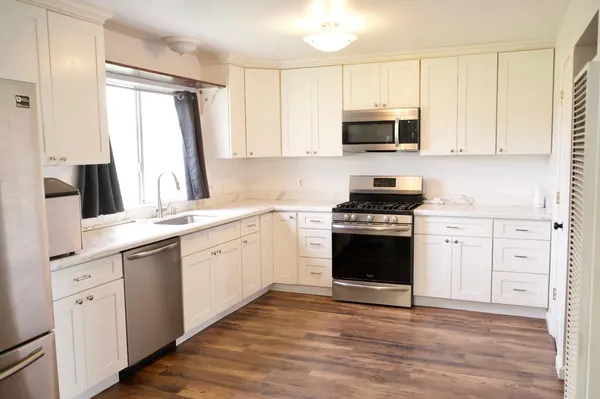 a kitchen with white cabinets and appliances