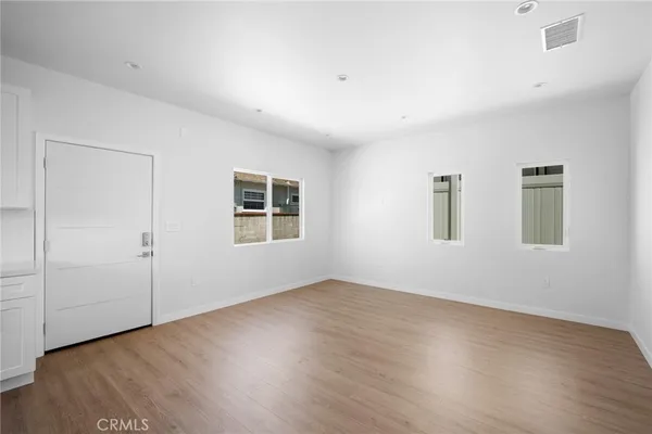 an empty room with wooden floor and windows