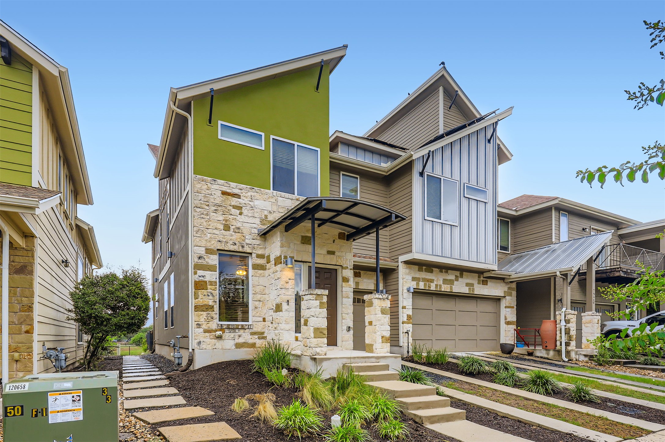 View of front facade with stone siding, an attached garage, board and batten siding, driveway, and stucco siding